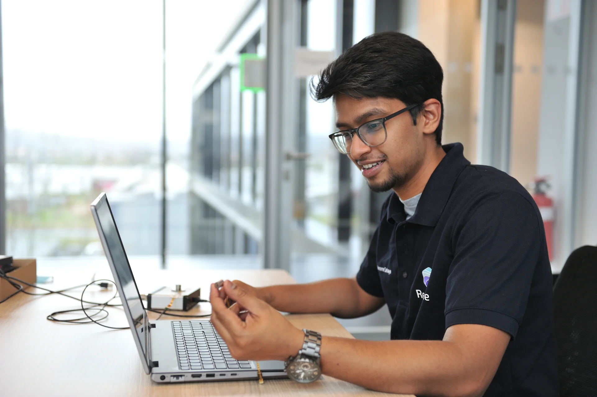 Mission Resense engineer analyzing miniature force torque sensor component while working on laptop